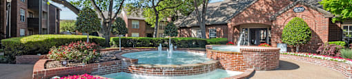 A pool surrounded by a brick wall and a flower bed.