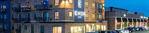The image shows a building with the word "END" on it, with cars parked in front and a clear sky in the background.