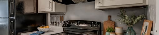 A black stove top oven sits in a kitchen with white cabinets.