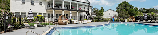 A large white house with a pool in front.