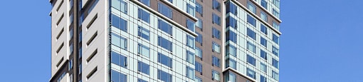 A modern multi-story building with glass windows and a street view in front.