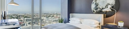A modern bedroom with a large bed and a view of the city.
