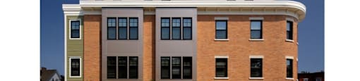 A multi-story building with a brick facade and a mix of window colors.
