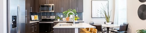 A modern kitchen with a refrigerator, sink, and dining table.