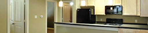 A kitchen with a black refrigerator and microwave at Centre Place Apartments, Denton, TX 