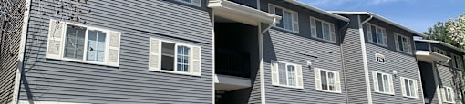a gray apartment building with white windows and a blue sky in the background