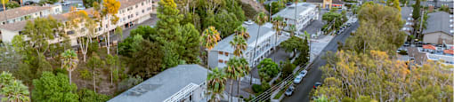 A building with a white roof is surrounded by trees and a road.