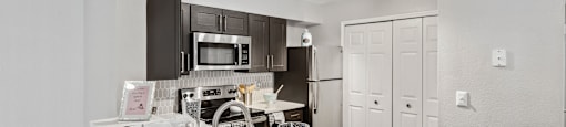 Fredericksburg Apartments for Rent - England Run North - Kitchen with Dark Cabinets, White Countertops, Breakfast Bar, and Appliances.