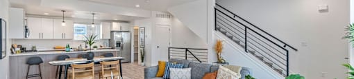 a living room with a couch and a kitchen with a staircase