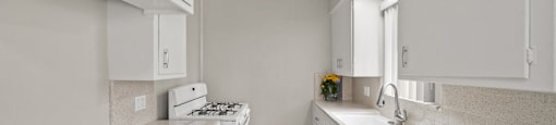 A kitchen with white cabinets and a countertop with a bowl of fruit on it.