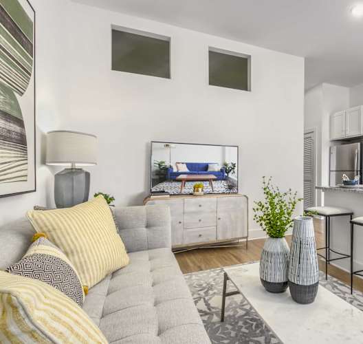 a living room with a couch and a kitchen with stools