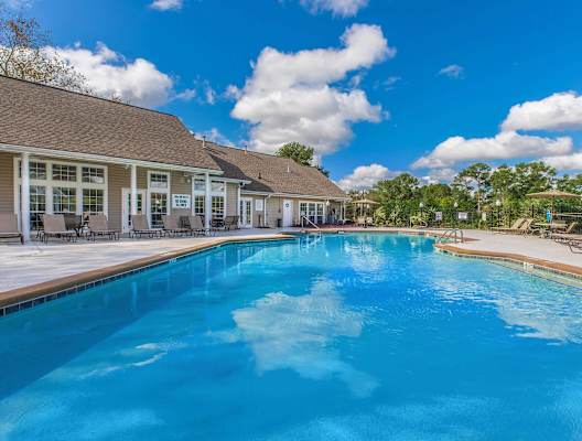 a large swimming pool with lounge chairs and a building in the background at Arbors at Windsor Lake, South Carolina, 29223