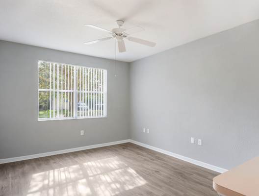 an empty room with a large window and a ceiling fan