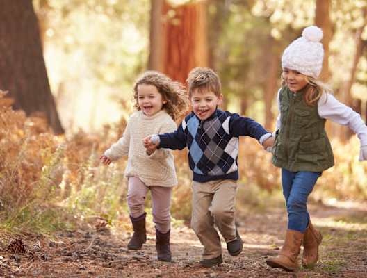 Group of Children in Winter Clothing Running in Forest