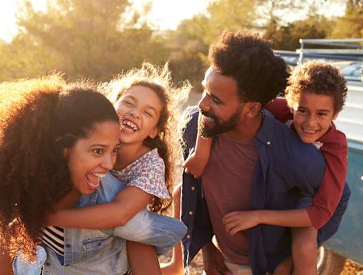 Mother and Father With Children On Backs Laughing