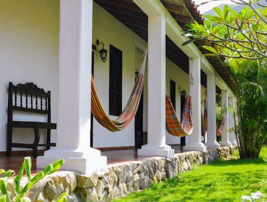 A porch with a bench and hammocks.