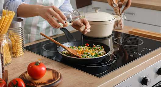 A person is cooking spaghetti in a pot on the stove.