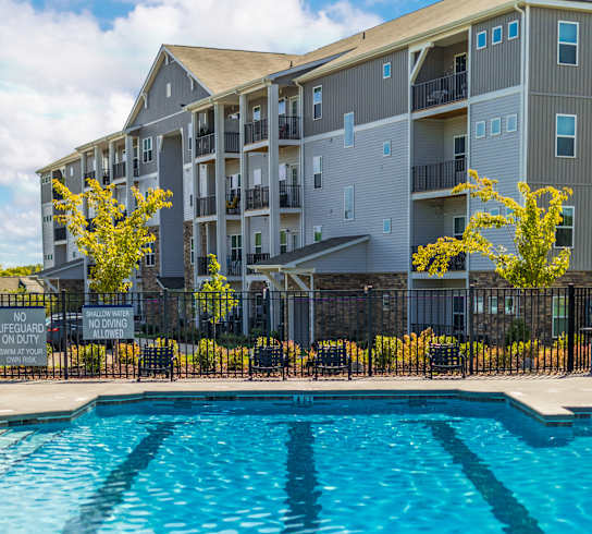 A swimming pool in front of a multi-story apartment building.