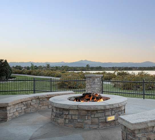 a fire pit and seating area on a patio with a view of a lake and mountains