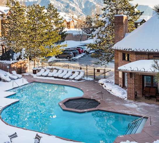 a swimming pool in the snow with mountains in the background