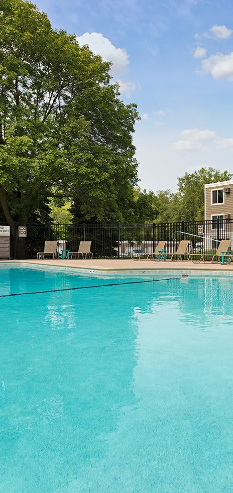 A swimming pool surrounded by trees and a fence. at Minnehaha Manor, Oakdale, MN