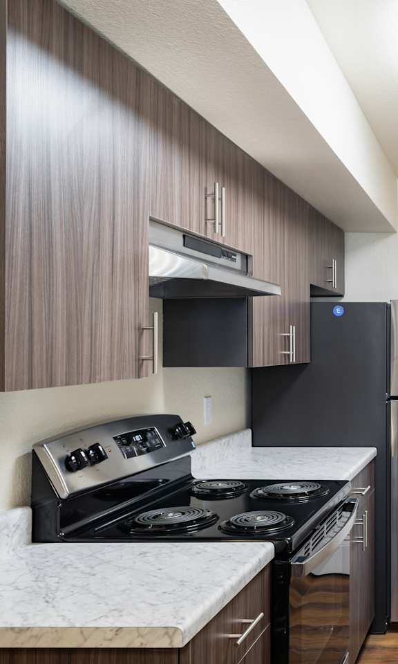 A kitchen with a white counter top and dark wood cabinets.