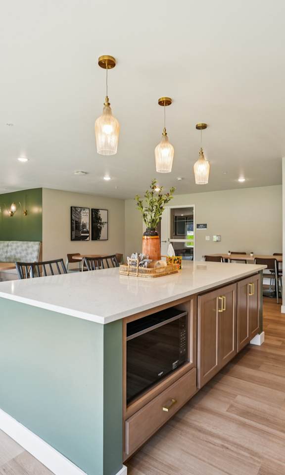 A kitchen with a green wall and wooden floors.