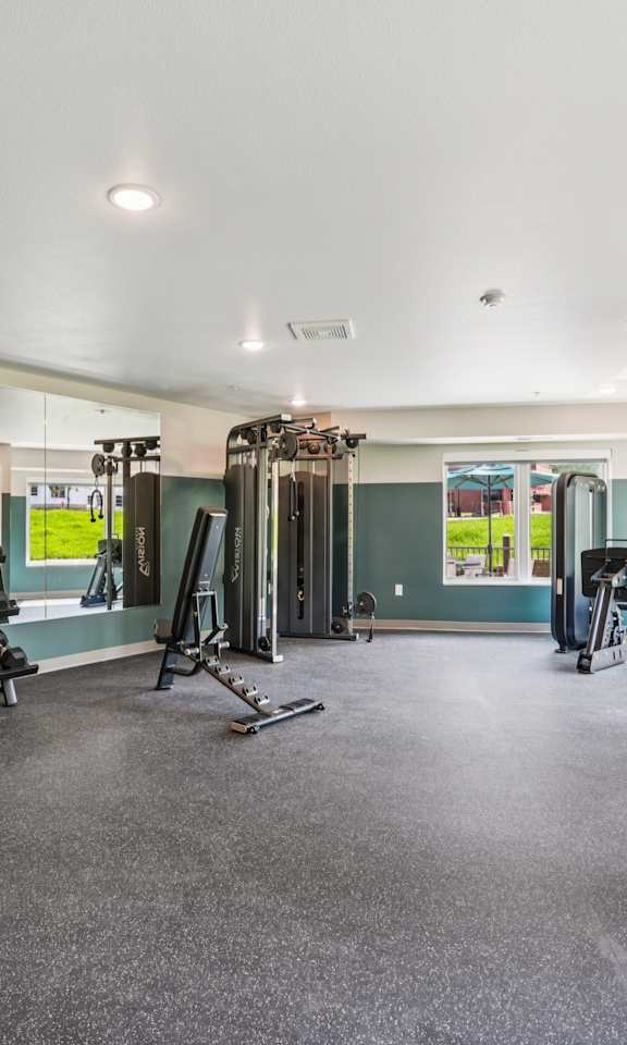 A gym with a variety of equipment including treadmills, weights, and exercise machines.