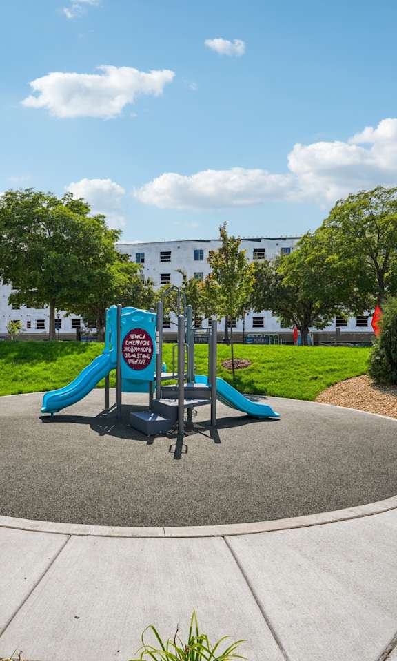 A playground with a slide and a bench in the foreground.