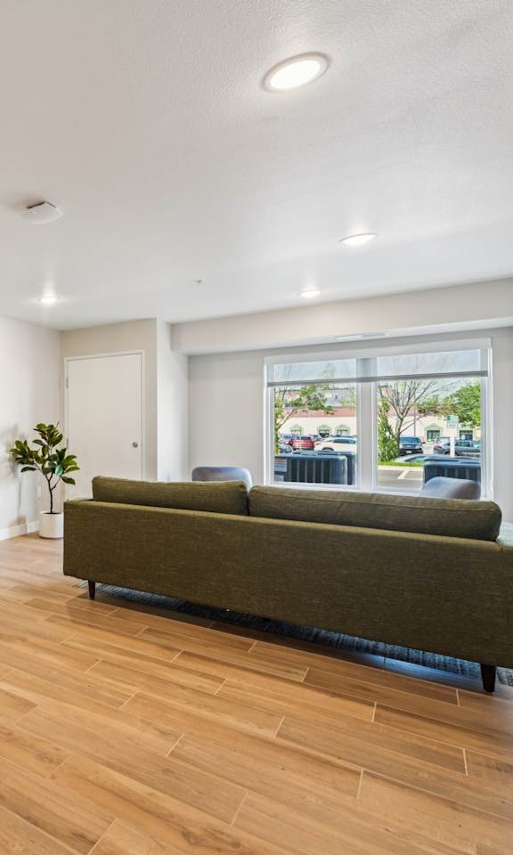 A room with a brown sofa and wooden flooring.
