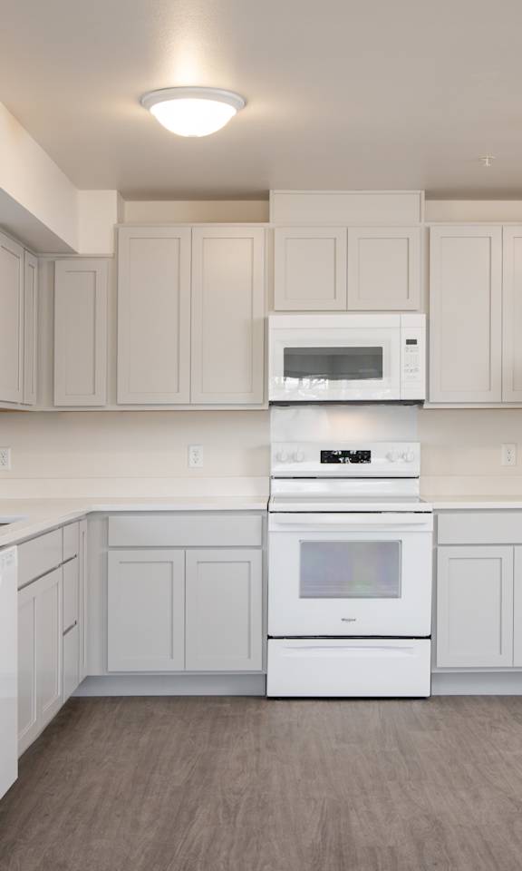 A white kitchen with a refrigerator, oven, and microwave.