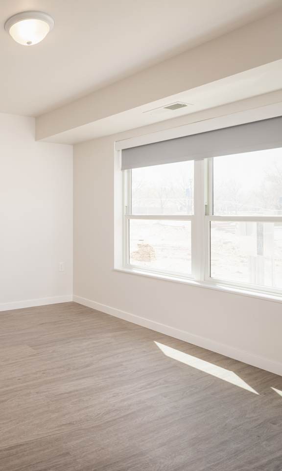 A room with a window and a wooden floor.