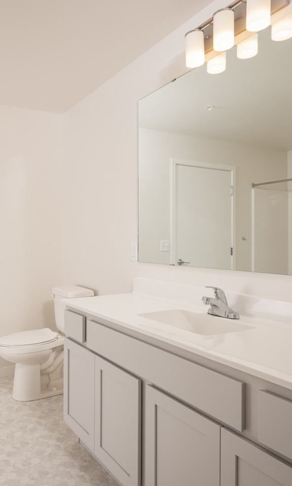 A white bathroom with a toilet, sink, and mirror.