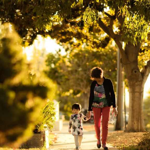 A woman and a child are walking down a tree-lined path.at Tigardville Apartments, Tigard, Oregon