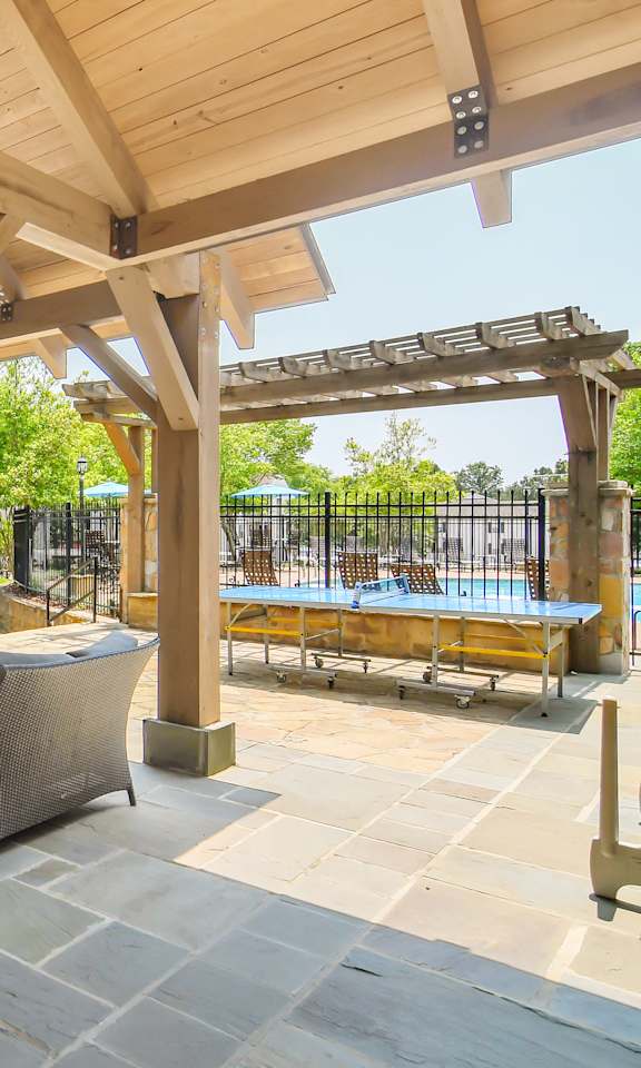 a patio with a table and chairs under a wooden pavilion