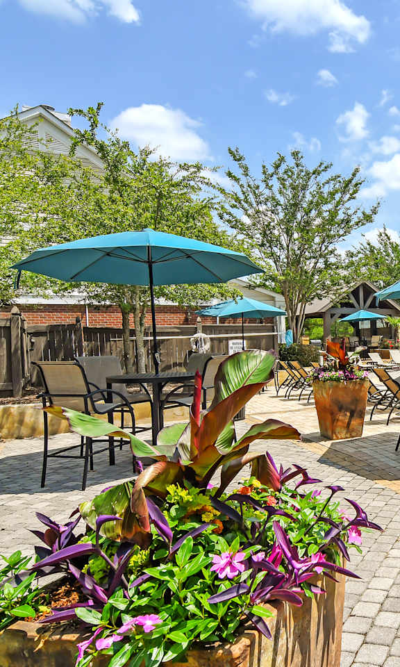 a swimming pool with patio furniture and umbrellas