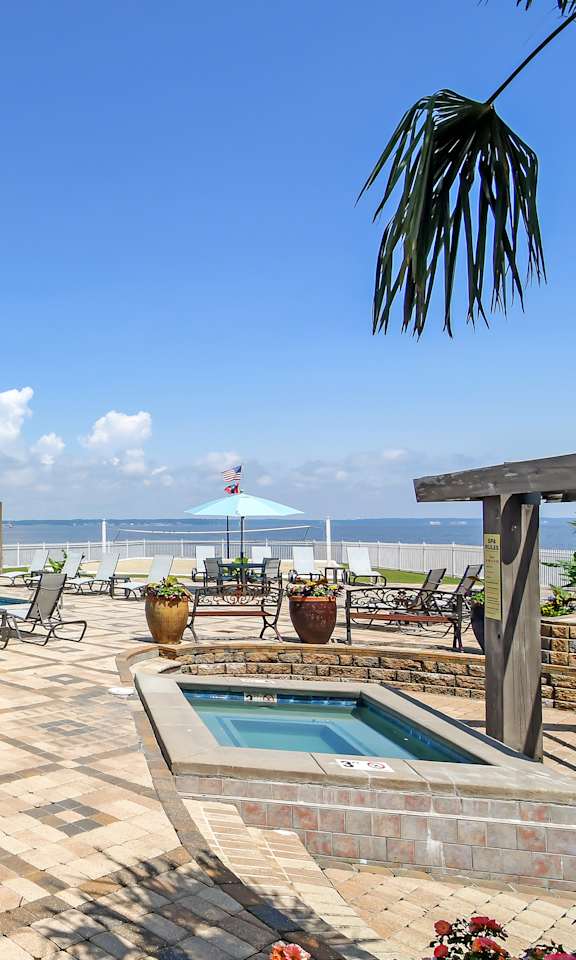 a swimming pool with tables and chairs on a patio overlooking the ocean at Lakeshore Pointe Apartment Homes, MS, 39047