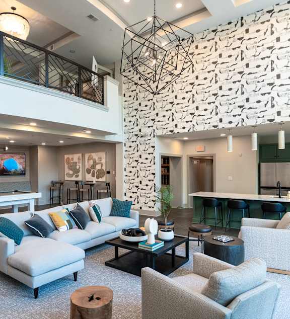 Clubroom with a wall of televisions, a shuffleboard table, a sectional sofa, and a bar-height kitchen counter.