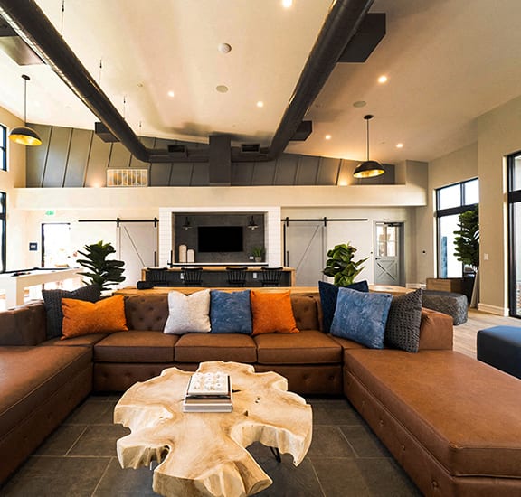 a living room with a large brown couch and a coffee table in front of a fireplace