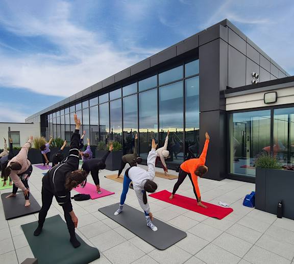 A group of people practicing yoga on mats outside a modern building