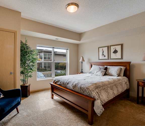 a bedroom with a bed and a chair and a window