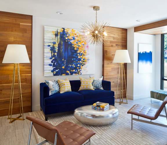 A blue couch with a yellow and blue painting behind it.