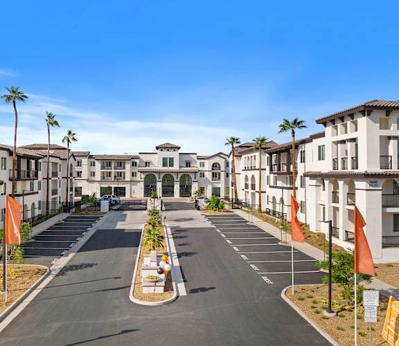 an empty street in front of apartments with palm trees at The Venue at Orange Apartments, Redlands, CA, 92373