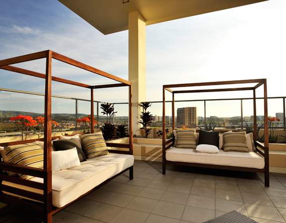 Two wooden daybeds with cushions and pillows on a patio.