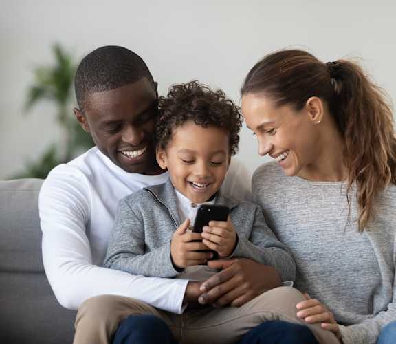 a family sitting on a couch looking at a cell phone