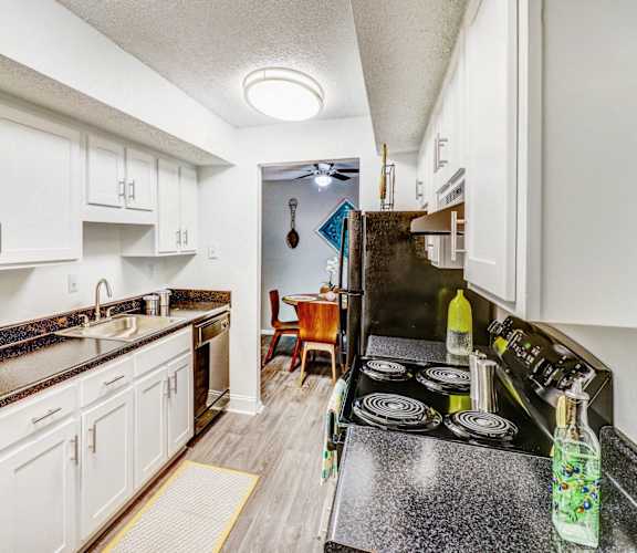 a kitchen with white cabinets and black counter tops