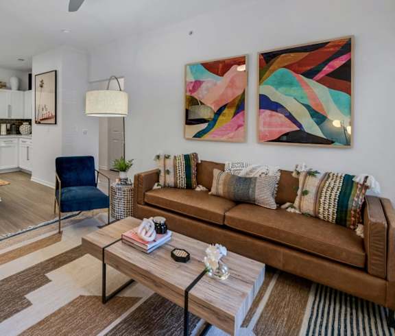 a living area with a couch coffee table and a kitchen in the background