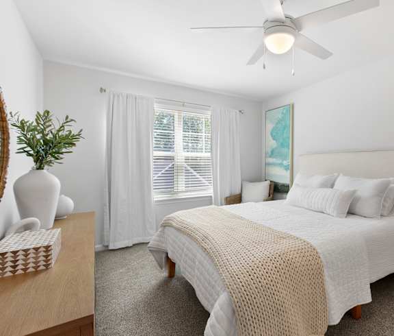 A bedroom with a large bed and a ceiling fan.