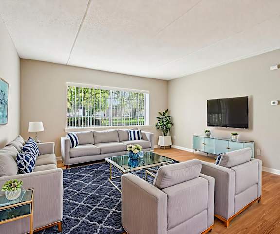 A living room with a grey couch, a glass coffee table, and a television.