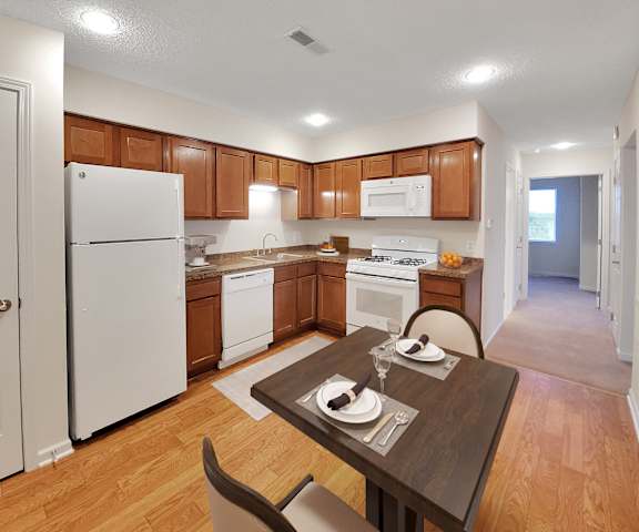 a kitchen with white appliances and wooden cabinets and a dining table